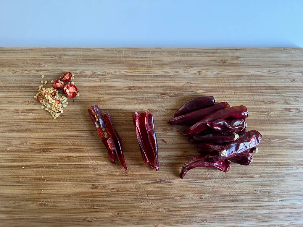 Chopped dry Cayenne Peppers with seeds removed laying on a wooden board.